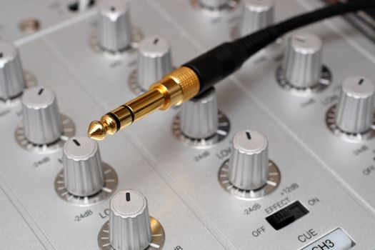 gold plug on dj music mixer close-up