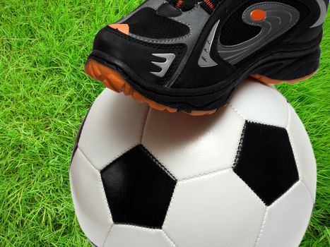 football shoe and soccer ball close-up over green grass field