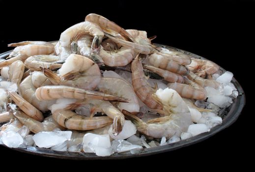 fresh raw shrimp piled high on crushed ice, isolated on black
