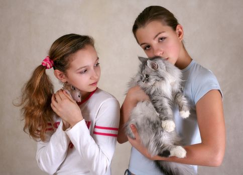 Two girls, one of them with a hamster, another with a cat