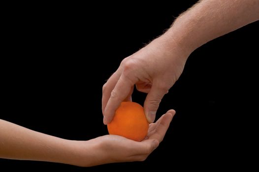 an isolated over black image of a caucasian man giving a caucasian child an lush juicy looking Orange.