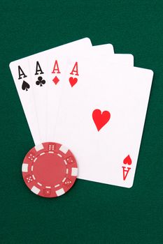 Four aces and red chip on green linen