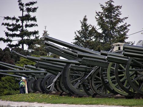 Two kids playng in front of WW II cannons at military museum.