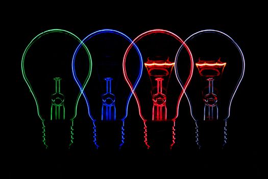 Four lights, symmetry, outline, lights, green, blue, red and white, white and red bulb lit with Contour Lines of metal coil. Against a black background
