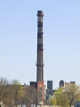 Single chimney of the industrial building against the blue sky