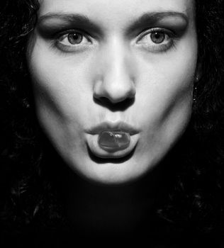 Black and white portrait of girl with jelly pastille in lips. Strong look.