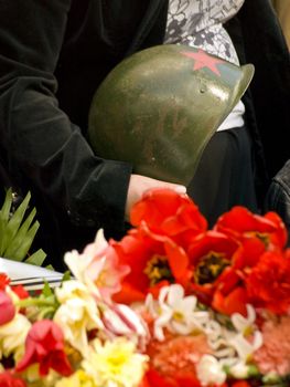 Old metal russian oldier hat in hands near the flowers