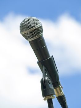 Single microphone against the blue sky with clouds