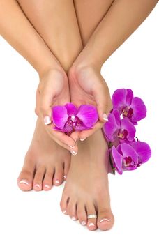 Pedicured feet and manicured hands with beautiful orchids