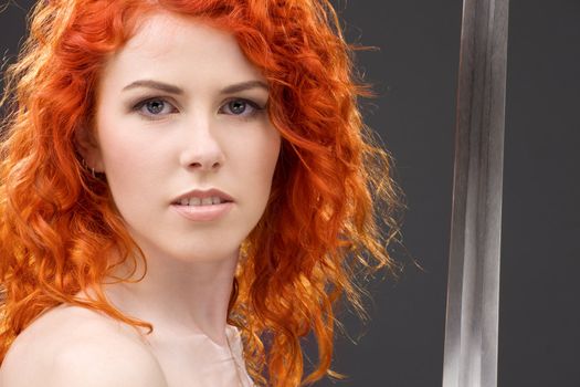 lovely redhead with medieval sword over grey