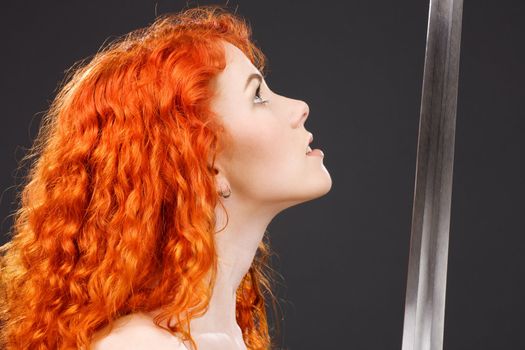 lovely redhead with medieval sword over grey