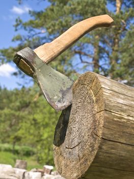Single axe in wood against the nature and blue sky