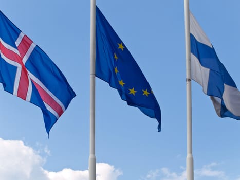 three different flags against the blue sky