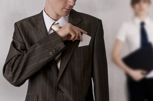 businessman putting a businesscard (with space for copy) into the pocket
