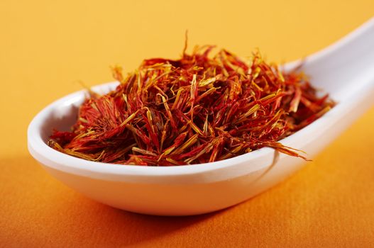 spoon of dried saffron on orange background