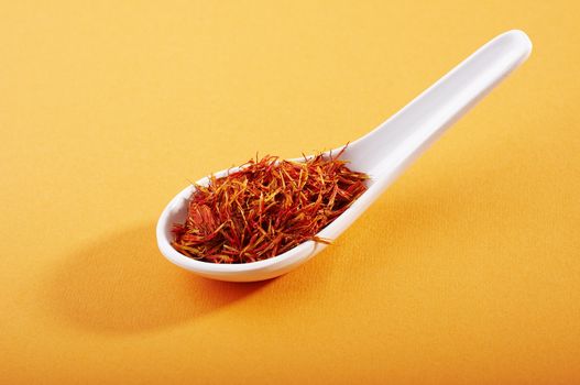 spoon of dried saffron on orange background