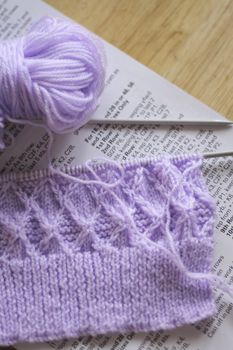 lilac knitting wool on needles and the pattern beneath