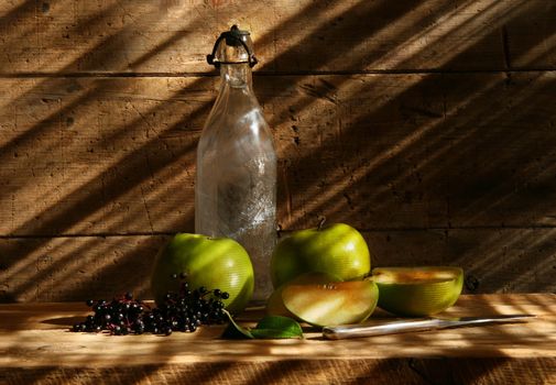 Old bottle and green apples with wood background