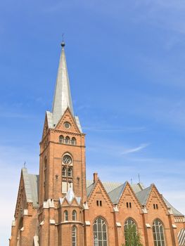 red brick Church against the blue cloudy sky 