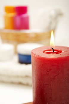 Candle front of the spa items (shampoo, towel, lotion)