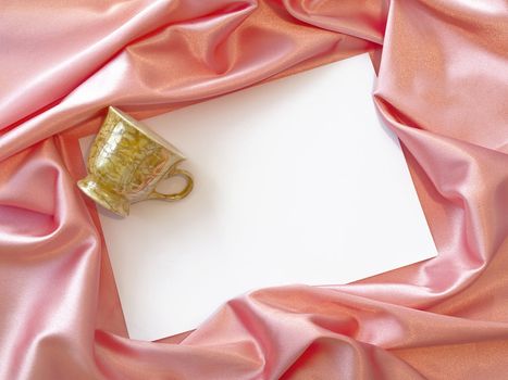 Pink silk textile border round white paper with mug