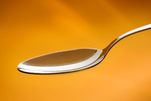 Empty metal spoon over a orange background