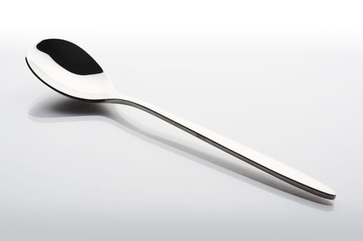 Small metal spoon over a white reflective background