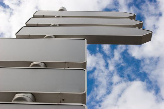 Signpost against blue sky with blank direction arrows