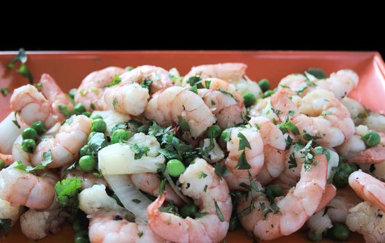 shrimp with peas, cauliflower, onion and cilantro on an orange platter