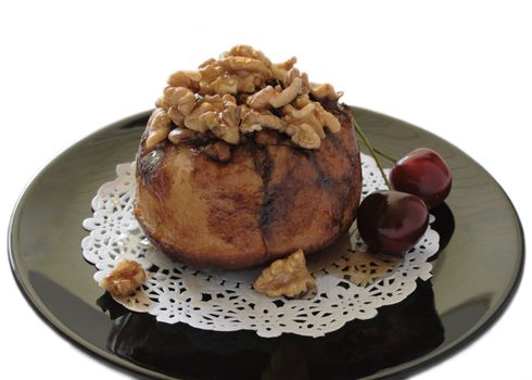 a sweet sticky bun with walnuts and fresh cherries on a black plate