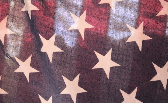 backlit old American flag showing stars over stripes