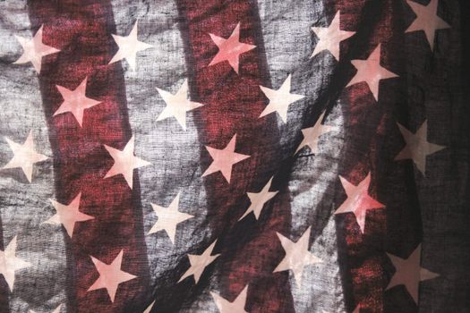 backlit old American flag showing stars over stripes