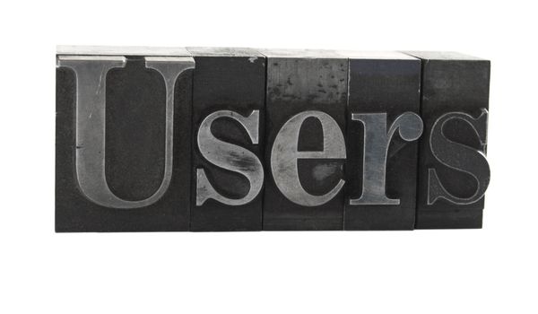 old, ink-stained metal letterpress type spells out the word 'user' isolated on white