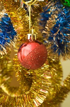Red ball for an ornament of a holiday among a bright tinsel