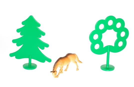 Toy plastic horse among toy green plastic trees