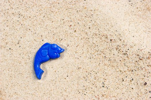 Lost toy fish on a sandy beach