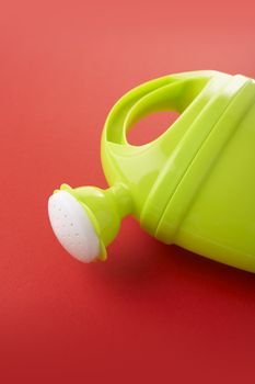 Plastic toy watering can on red background 