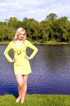 The beautiful girl stands on the bank of the river