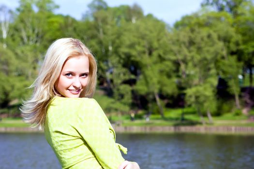 The beautiful girl stands on the bank of the river