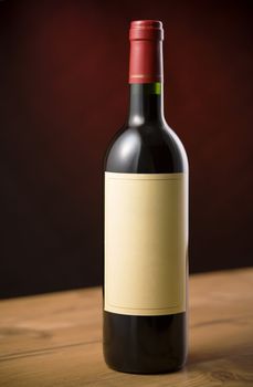 Red wine bottle on wooden table over dark red background