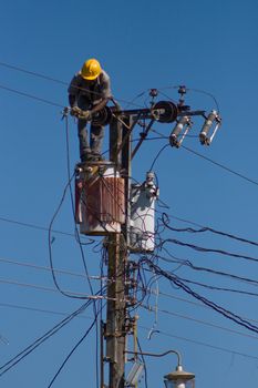 Electrician stays on the tower pole and repairs a wire of the power line
