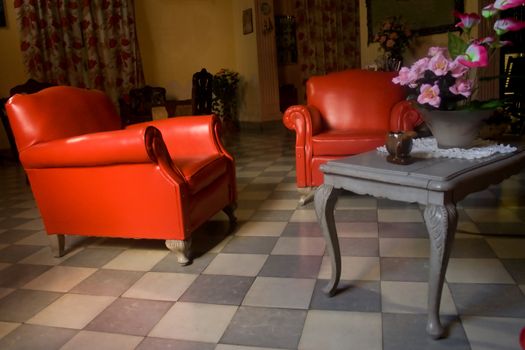 Interior: red chairs and a table with flowers in vase. Camaguey, Cuba.