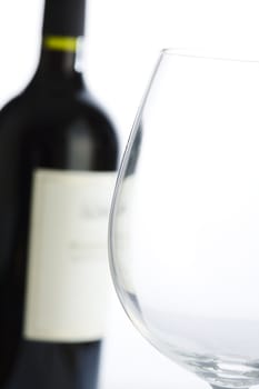 Close up of glass with red wine bottle on background