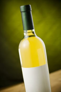 White wine bottle on wooden table over dark green / yellow background