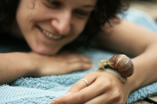 Woman holding snail on her hand and smiling