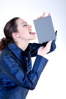 Portrait of a woman with long curly hair putting her tongue against a grey card