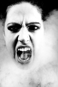 Portrait of a woman with long curly hair screaming out from smoke