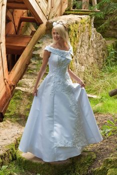 Beautiful blonde bride in white dress on the old mill