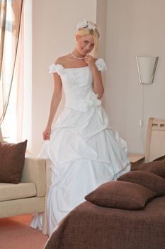 Beautiful blonde bride in white dress in interior