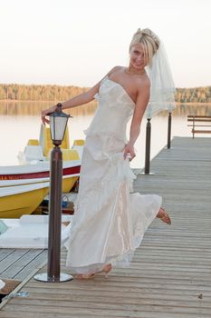 Beautiful blonde bride in white dress on the lake